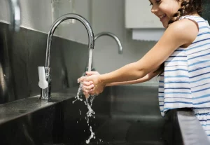 Smiling girl washing her hands at a sink, enjoying clean and reliable water.