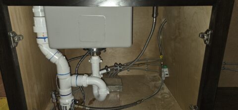 Under-sink plumbing installation with white PVC pipes, drain lines, and supply connections for a kitchen ice maker in Prosper, TX
