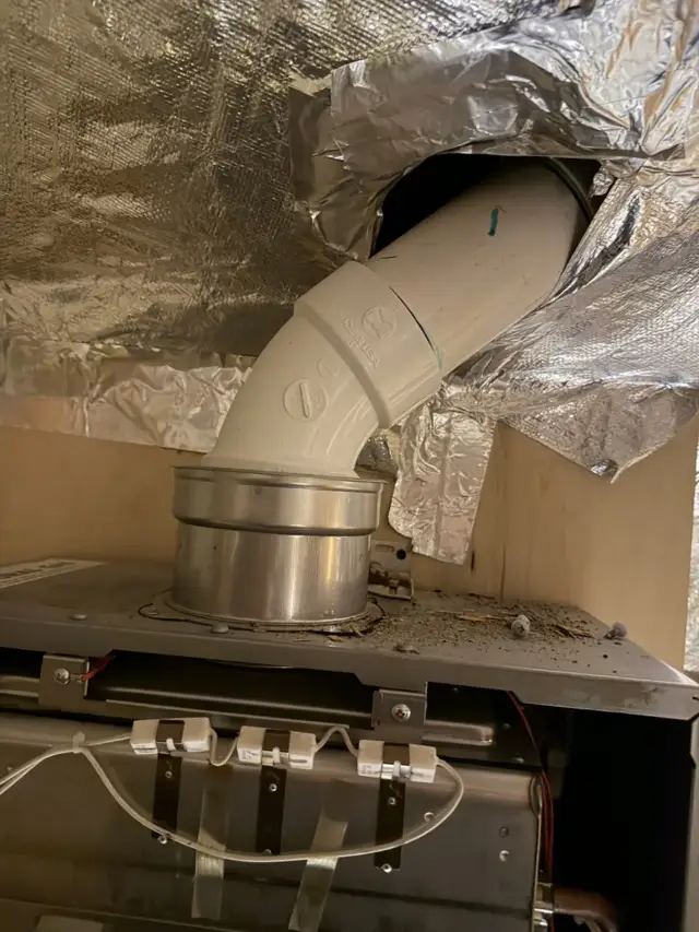 Improper tankless water heater venting installation in Frisco attic showing code violations.