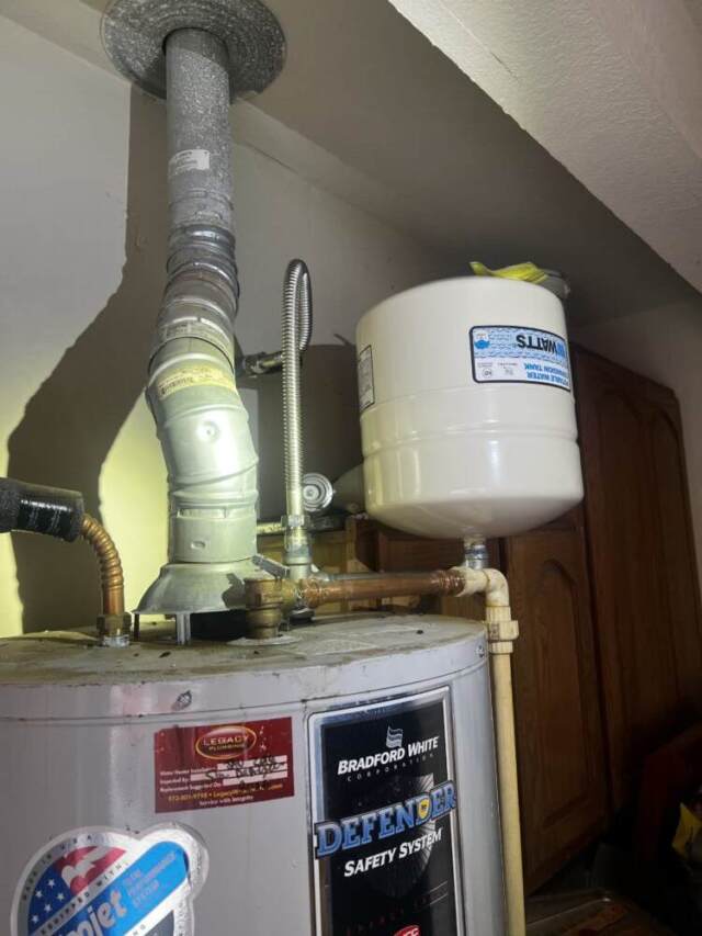 Newly installed expansion tank mounted above a residential water heater.