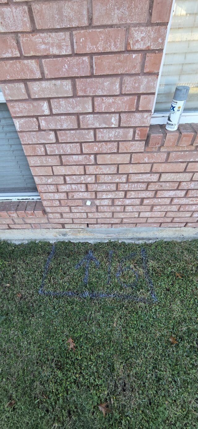 Spray paint markings on grass showing the exterior location of a slab leak.