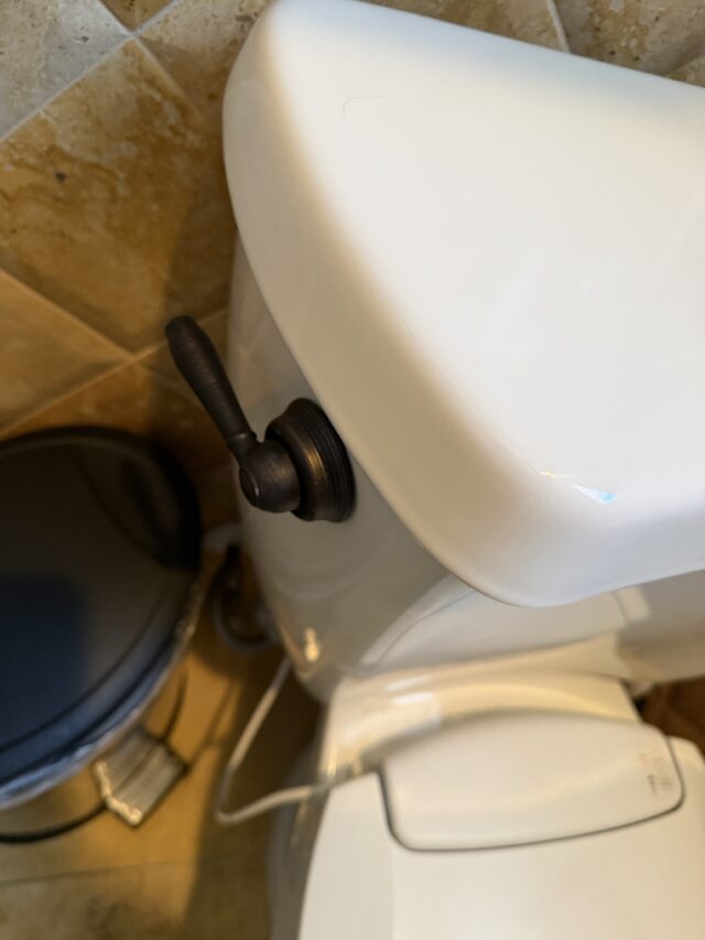 Close-up of replaced toilet handle and flapper after repair.