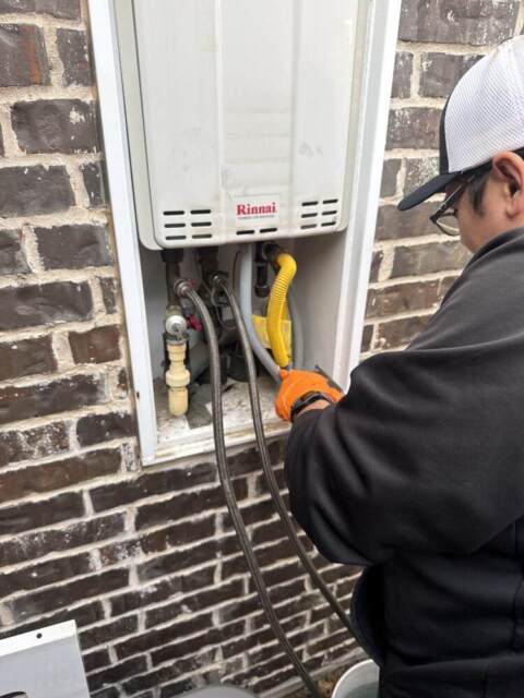 Plumber Eron performing routine maintenance and flushing a tankless water heater